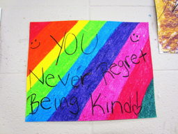 Hand-made rainbow-striped poster reading, "You never regret being kind"